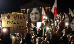 Люди, що тримають плакати та фотографії вбитої журналістки Дафни Каруани Галізії біля кабінету прем'єр-міністра у Валлетті.