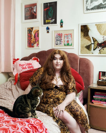 A woman sits on her bed next to a cat