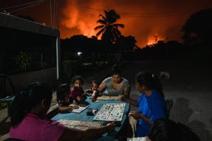 Neighbours play board games under a sky lit by gas flares, Punta de Mata, Venezuela, 5 November 2022