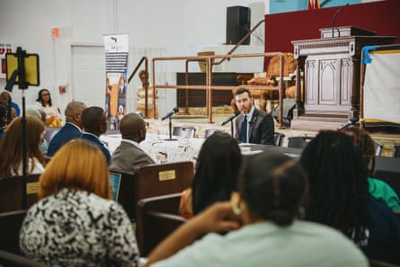 A man speaks into a microphone before a crowded church full of people