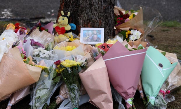 Bouquets laid around a tree with a photo of children placed atop the flowers