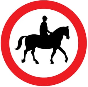 "Road sign from the driving theory test showing a person riding a horse in a red circle"