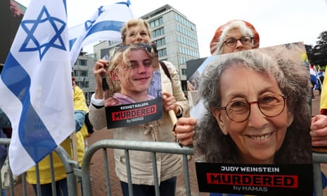people behind barrier with Israeli flags and pictures of women with signs under them saying 'Murdered'