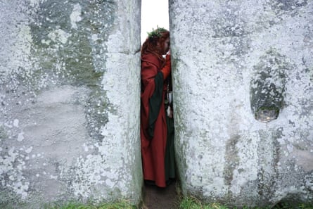 A woman stands with her head pressed against the stones of Stonehenge
