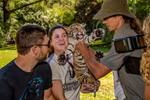 People pose for a photo with a tiger cub