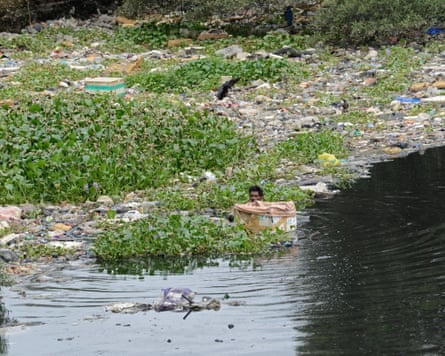 a man collects trash in a river