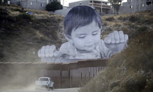 A Border Patrol vehicle drives in front of a 20m mural of a boy at the US-Mexico border wall.