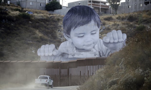 A Border Patrol vehicle drives in front of a 20m mural of a boy at the US-Mexico border wall. 