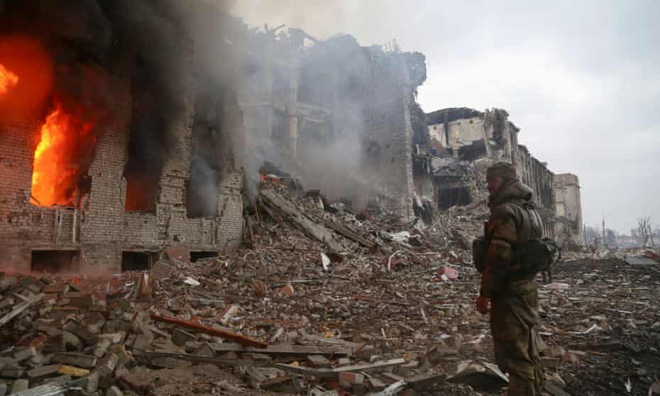 A service member of pro-Russian troops stands in front of a destroyed administration building in Mariupol. Officials estimate that 100,000 people are currently trapped in the city.