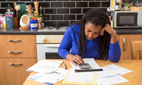 Woman sits at her kitchen table at home checking over the household bills