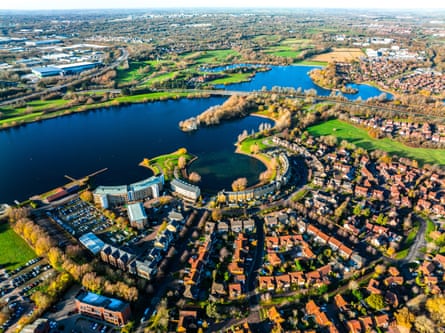 Aerial view of Milton Keynes suburban housing with curved streets surrounding a lake and parkland