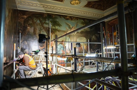 A craftsman on a scaffold works on the painting during the restoration
