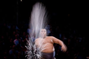 A sumo wrestler throws salt in the air