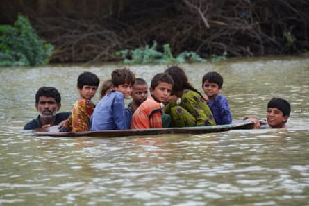 A man and a boy use a satellite dish as a boat to move children across a flooded area after heavy monsoon rainfalls in Jaffarabad, Pakistan