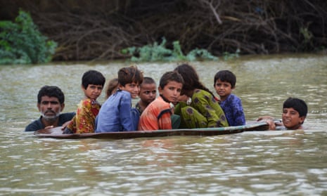 Children float on an upturned satellite dish in floodwater in Pakistan.