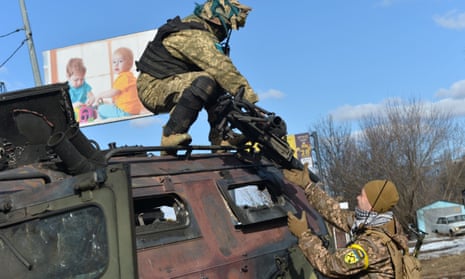 A Ukrainian fighter takes the automatic grenade launcher from a destroyed Russian vehicle after the fight in Kharkiv on 27 February.