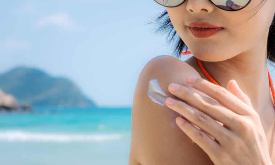 Woman applies sunscreen on the beach