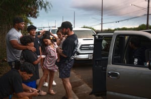 people with children on the side of a road next to cars