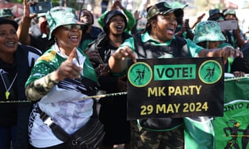 Smiling people in green hats with a poster reading: 'Vote! MK Party, 29 May 2024'.