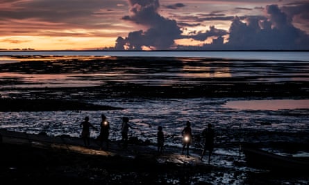 Children fish by the light of mobile phones in Boigu Island