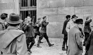 The work of Hungary’s state security agency – Államvédelmi Hatóság or ÁVH – created a climate of fear, and it was much hated. During the revolution some of its members were publicly lynched. Here some leave their headquarters after rebels stormed the building