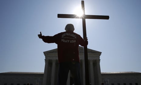 A campaigner holds a cross as he prays prior to rulings outside the supreme court on Capitol Hill in Washington.