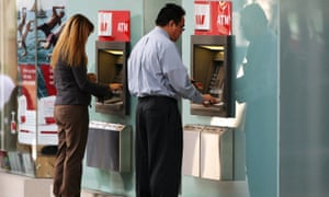 Two people using Westpac ATMs.