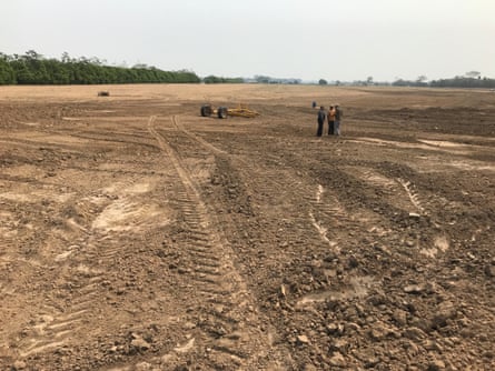 تمتد منطقة ترابية مسطحة تمامًا وبلا حياة مع آثار إطارات على مسافة بعيدة، مع ظهور بعض الغابات المتبقية على يسار الصورة. ثلاثة شخصيات تتحدث على مسافة متوسطة