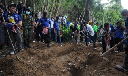 Rescue workers and forensic officials dig out skeletons from shallow graves following the discovery of an abandoned jungle camp in southern Thailand in May 2015.