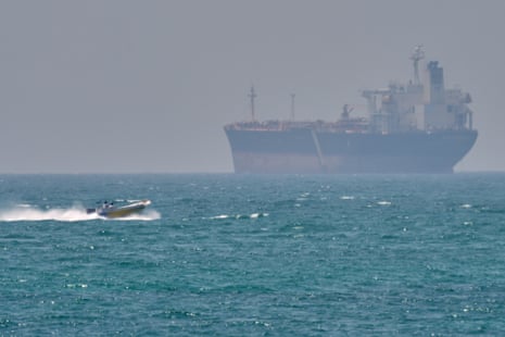 A boat sails past a tanker anchored on the Strait of Hormuz off the coast of Qeshm island
