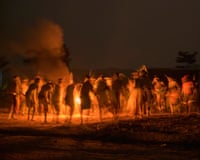 People dance around a fire at night