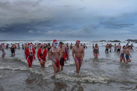 Swimmers in fancy dress emerge from the sea on a cold day at Christmas