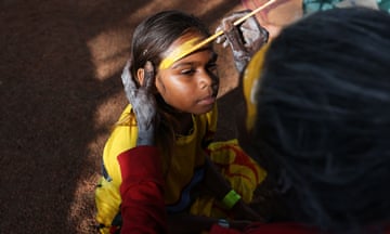 A girl has yellow paint applied to her forehead