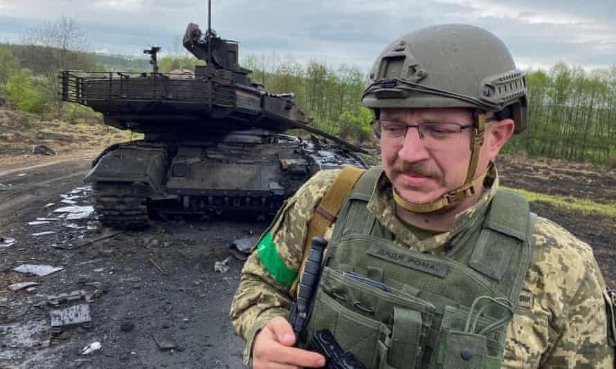 An unidentified Ukrainian serviceman walks next to a destroyed Russian battle tank near the village of Staryi Saltiv in the Kharkiv region, on Monday