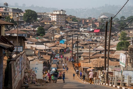 A road running downhill between slum houses.