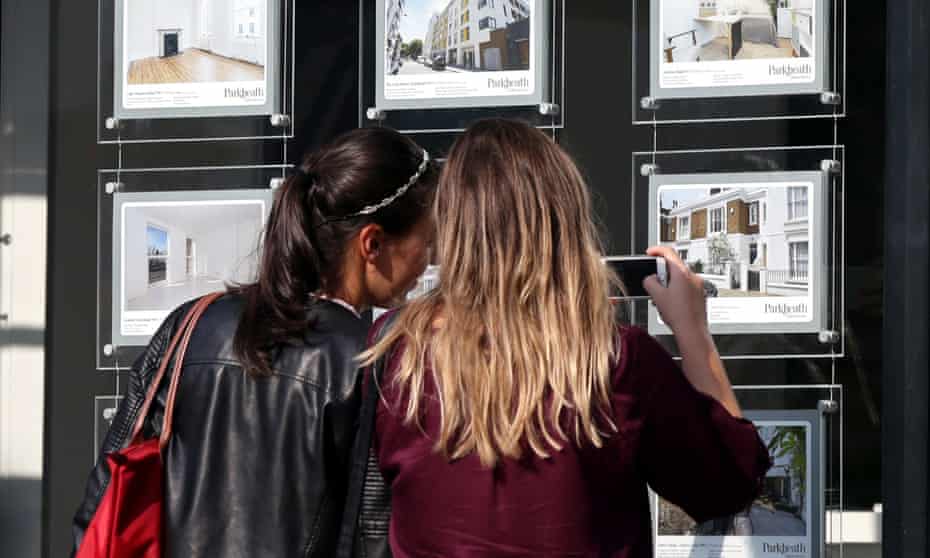 Two woman looking at houses for sale in an estate agent's window
