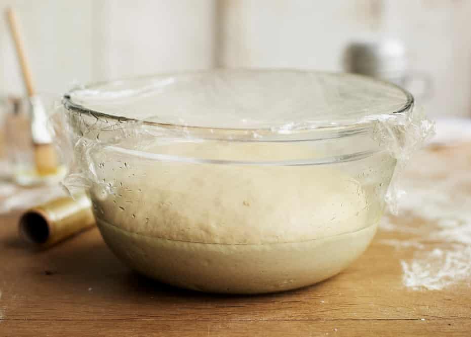Bread dough rising in a bowl covered with clingfilm