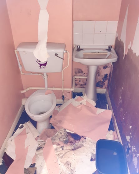 Toilet with no seat, mould and peeling wallpaper on floor