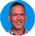 man in plaid shirt smiling with blue background