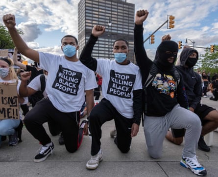 Protesters raise their fists as they kneel in front of a police station in Detroit, Michigan, on Saturday.