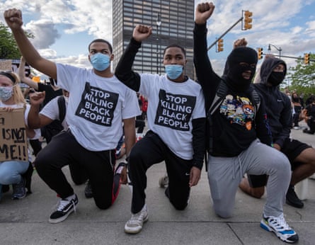 Protesters raise their fists as they kneel in front of a police station in Detroit, Michigan, on 30 May.