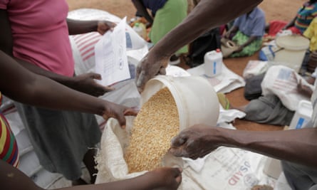 A woman pours food aid into a sack at a distribution point for Mafomoti primary school in Zimbabwe’s Mwenezi district