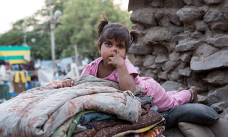 A young girl in a pink pyjama is laying on a pile of blankets and pillows on a market place on March 28, 2013 in Bijapur, India
