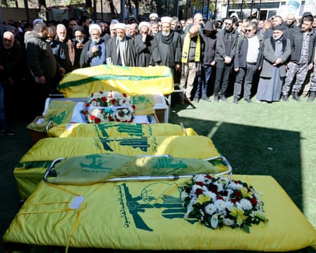 Mourners gather around the Hezbollah-draped coffins of people killed in Israeli airstrikes on Baalbek, during their funeral in the city of Baalbek.