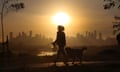 A woman walks her dog as the sun rises over Melbourne, Australia