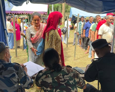 People rescued from an area cut off by flash flooding line up to register at an army camp in Nepal's Nuwakot district on Friday