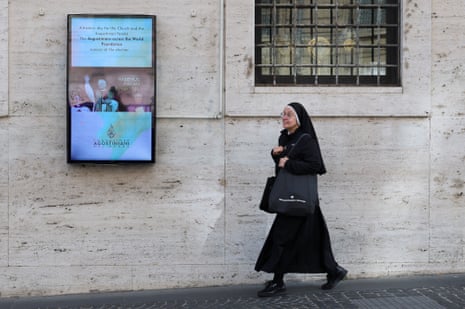 A nun walks past a screen displaying an image of the newly elected Pope Leo XIV near the Vatican, 9 May.