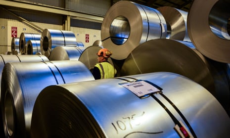 Worker walking past rolls of steel