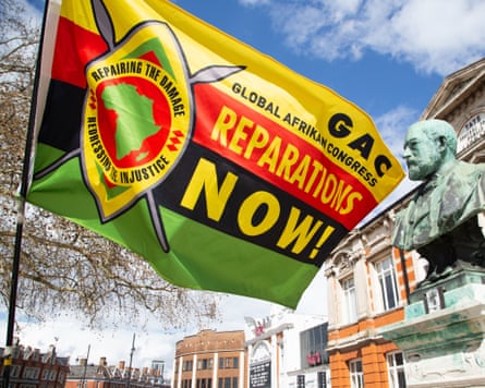 A man holds a flag calling for reparations in Windrush square.