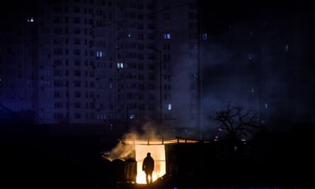 Man silhouetted against small area of flame in a mostly dark scene